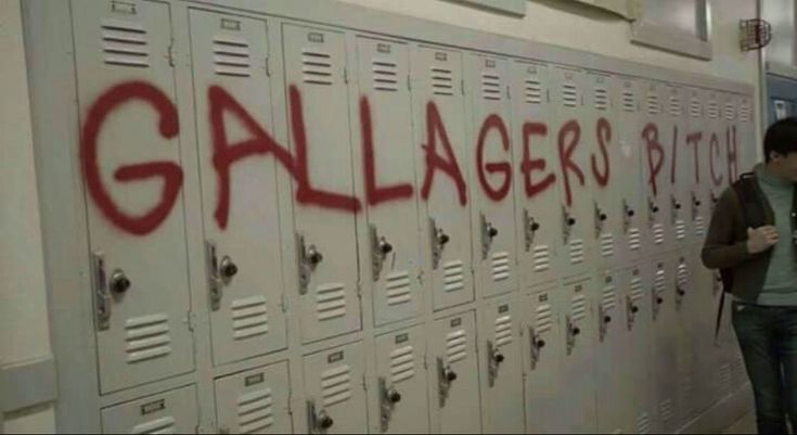 a man standing in front of lockers with graffiti on the wall next to it