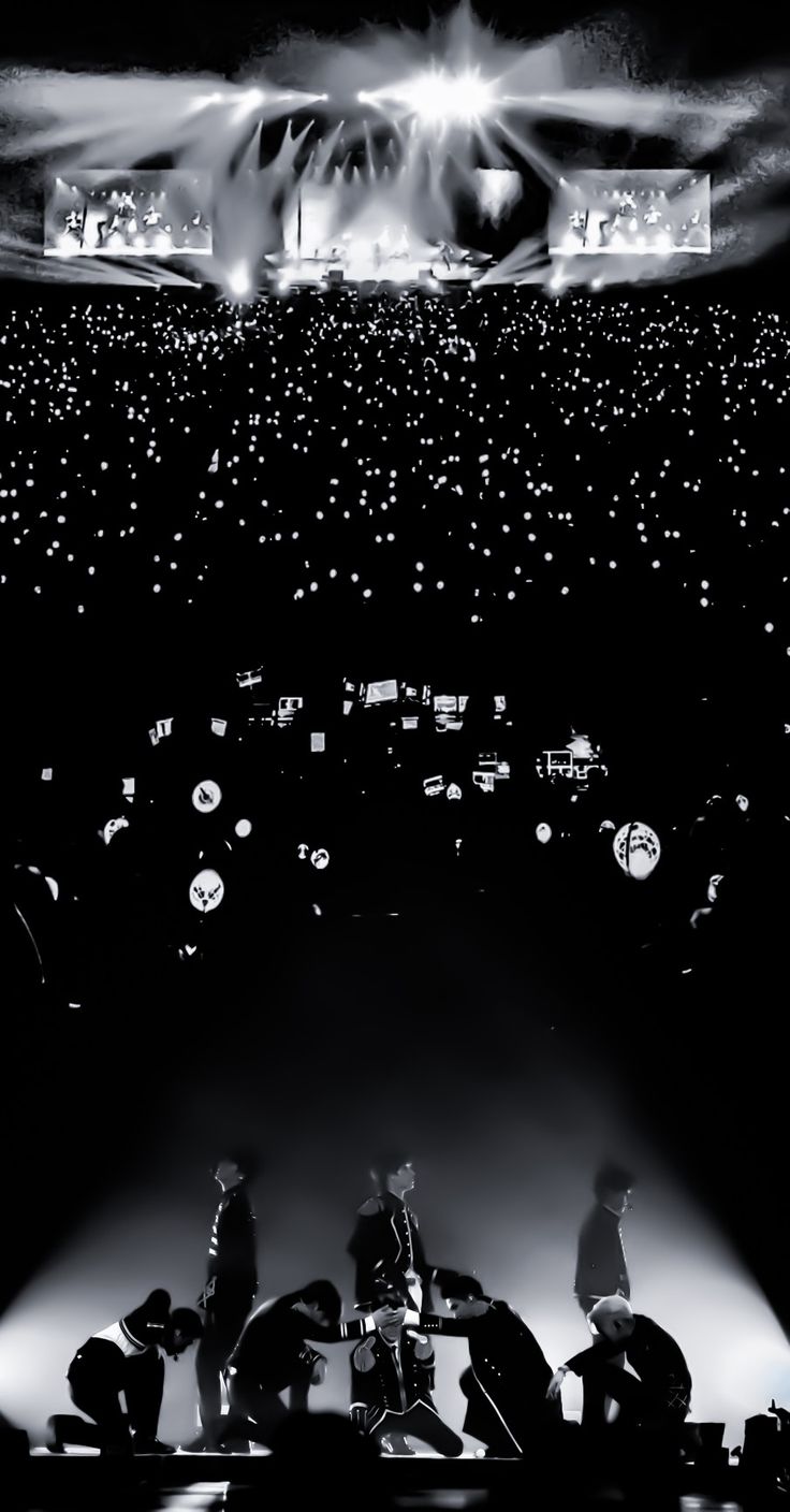 a group of people standing on top of a stage with lights in the air above them