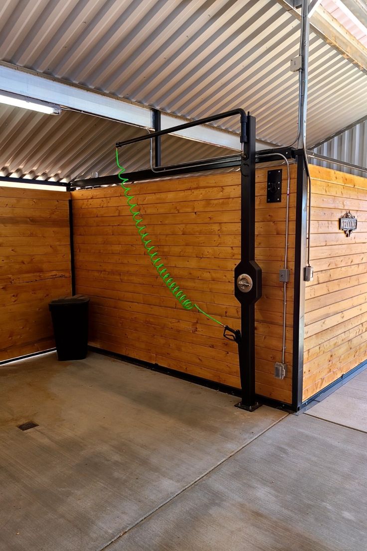 the inside of a building that has a wooden fence and metal poles on it, with a black trash can next to it