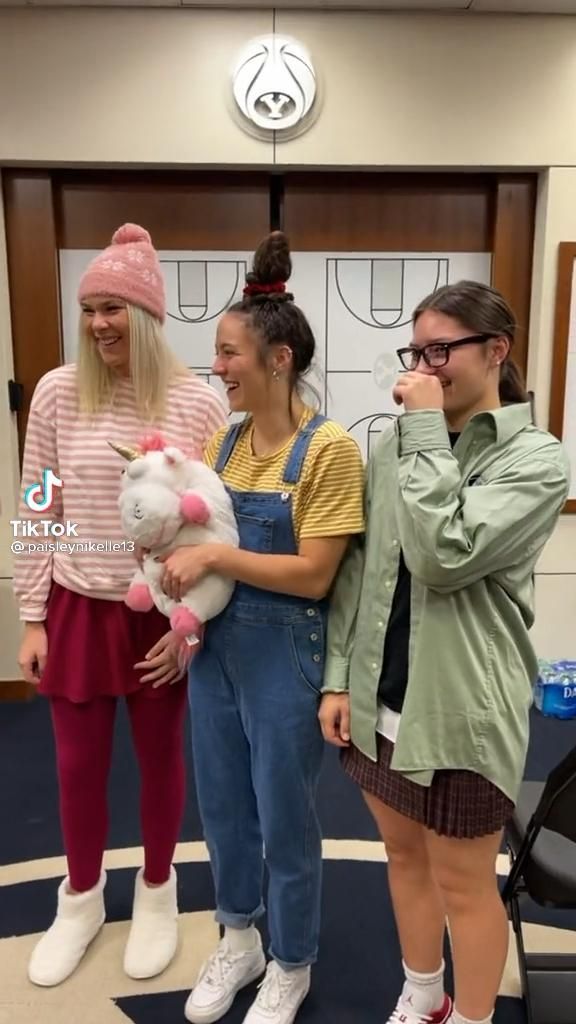 three girls in overalls are holding stuffed animals and talking to each other on the phone