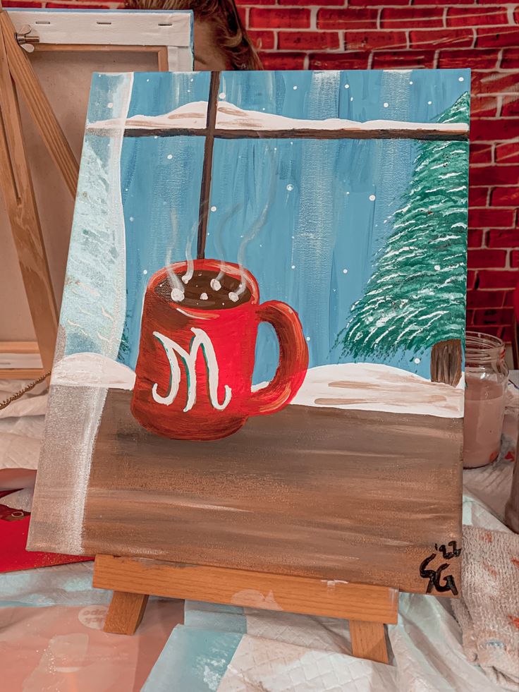 an acrylic painting of a red coffee cup with the letter m on it