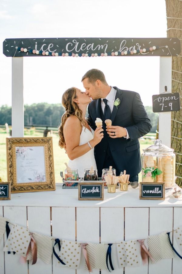 a bride and groom kissing in front of an ice cream stand at their wedding reception