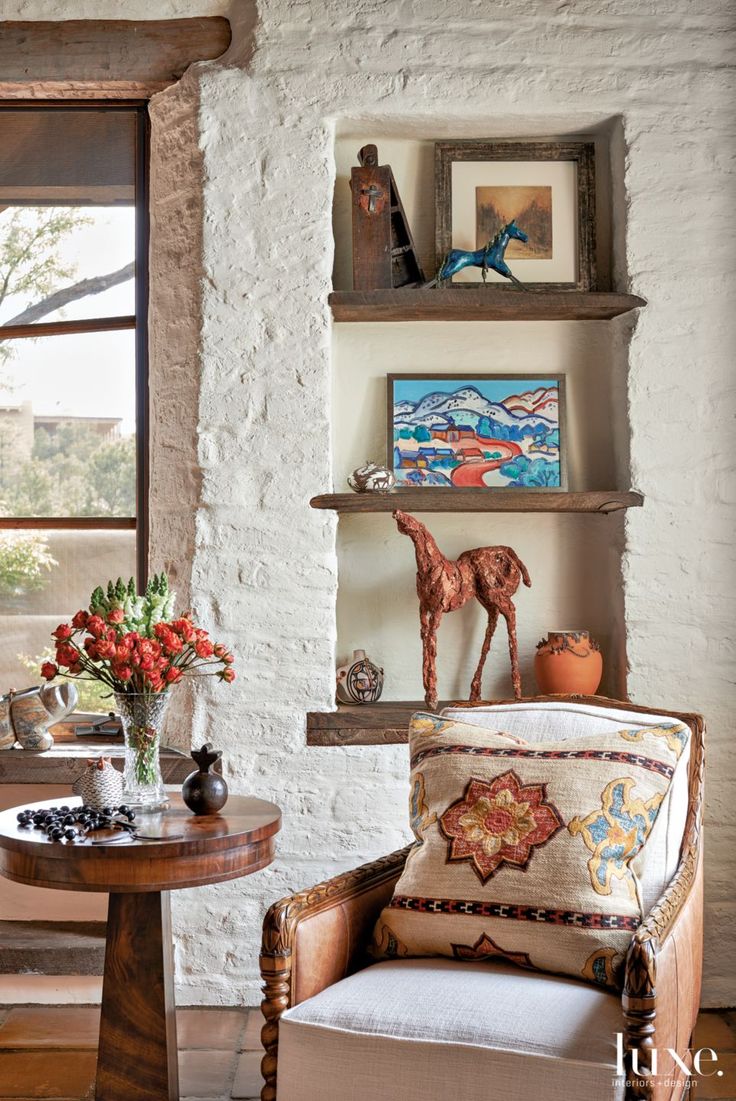 a living room filled with furniture next to a wall mounted shelf full of pictures and vases