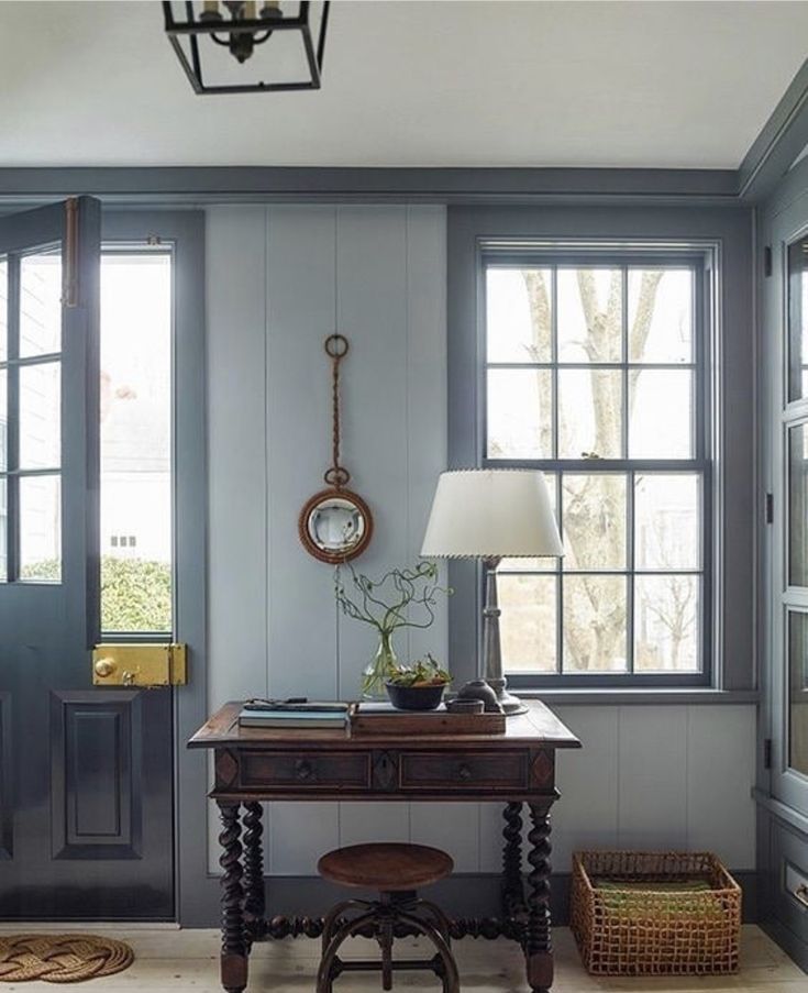 a room with blue walls and wooden floors has a lamp on the table next to it