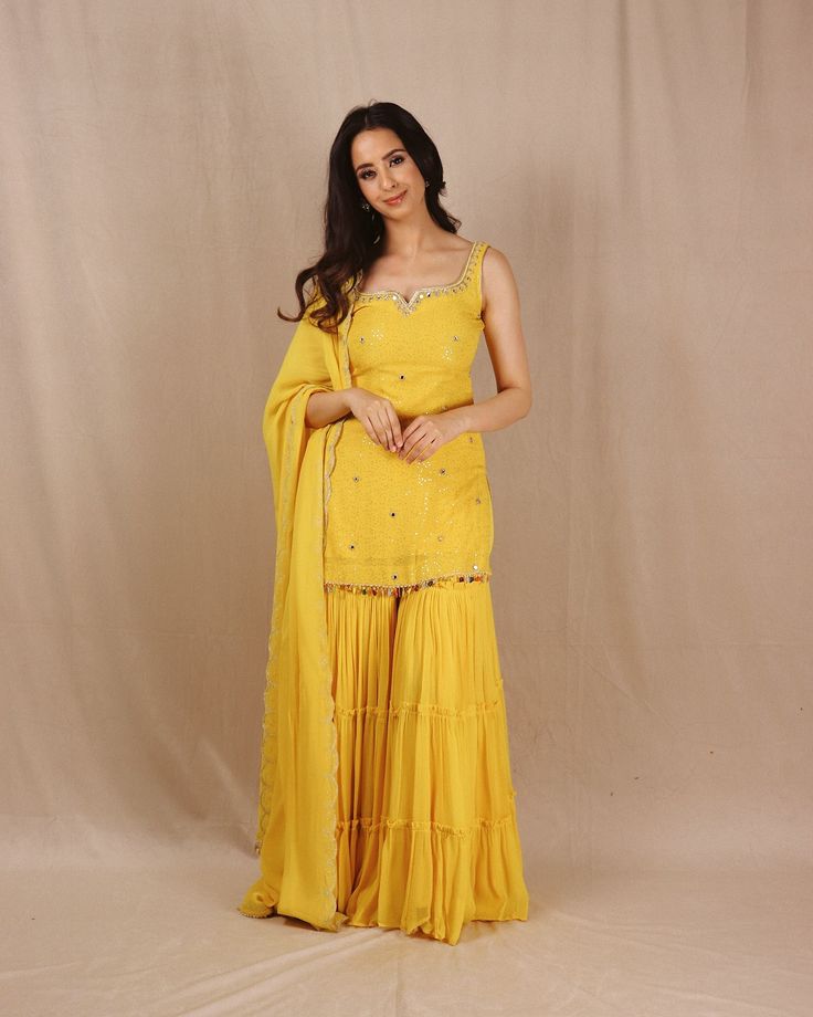 Introducing “Genda Phool”. The perfect sunshine yellow color to wear on your BFF’s Haldi. This stunning yellow kurta is crafted from crepe georgette with a luxurious 3-layered sharara. Adorned with intricate handwoven mirrors on the neckline and throughout the shirt, it features a beautifully handworked dupatta with colored tassels for a perfect finish. Shop our collection now. DM or email to book an appointment. #haldioutfit #haldidress #yellowsuit #shararadesign #shararasuits #shararad... Yellow Organza Sharara, Haldi Ceremony Outfit For Women, Yellow Dress For Haldi Function Pakistani, Yellow Kurta Woman, Yellow Kurti Design For Haldi, Simple Yellow Dress For Haldi Function, Yellow Sharara For Haldi, Haldi Ceremony Outfit For Sister Indian, Unique Haldi Outfits