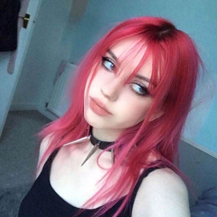 a woman with pink hair and piercings is posing for the camera in her bedroom