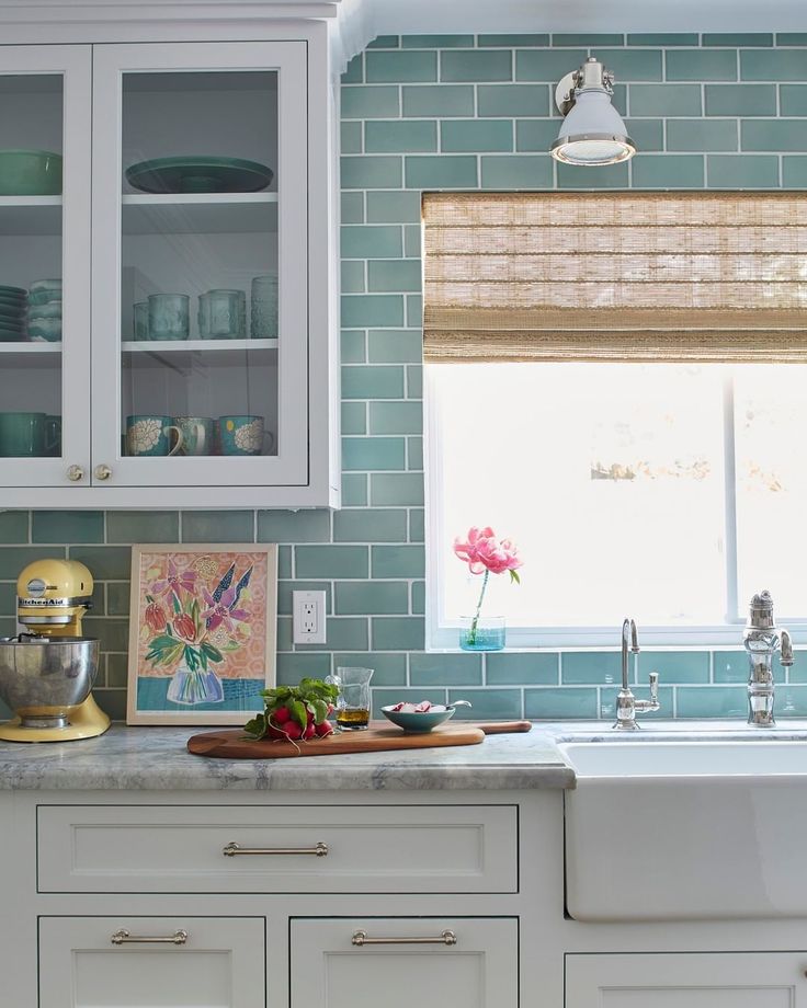 a kitchen with white cabinets and green tile backsplashing on the counter top