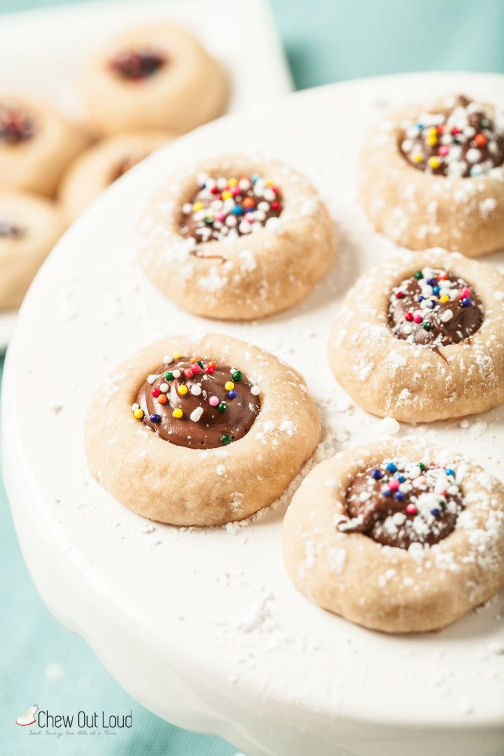 cookies with chocolate frosting and sprinkles are on a white platter