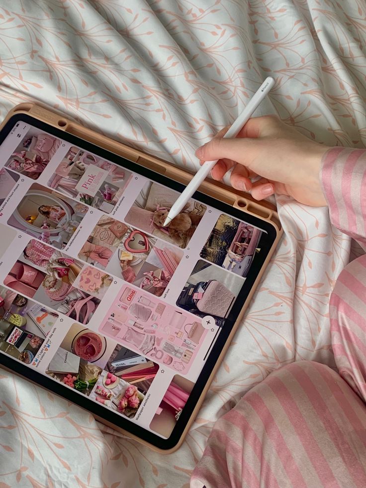 a person laying on a bed with a laptop and pen in their hand while holding the screen