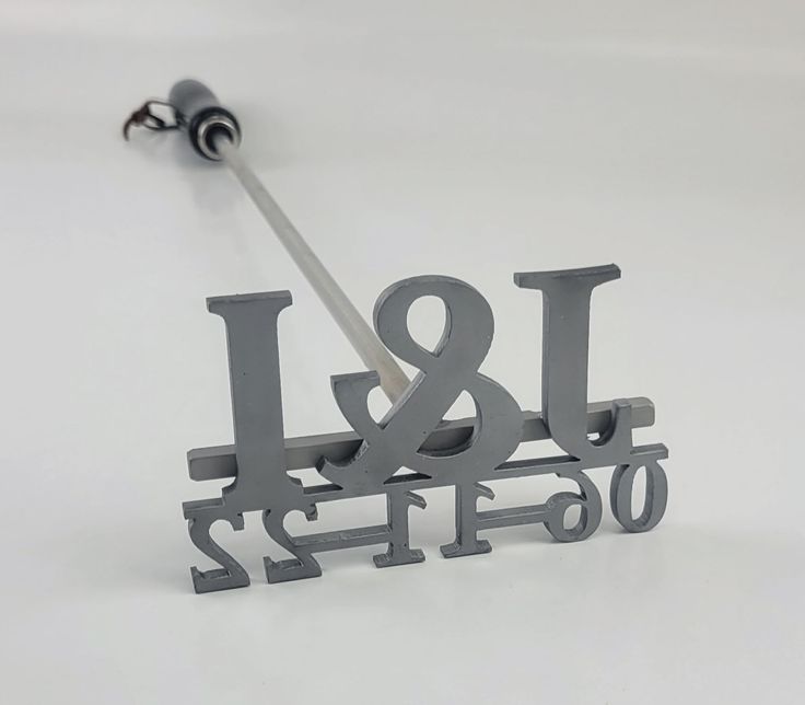 a pair of metal letters and numbers on a white surface with a light saber in the middle