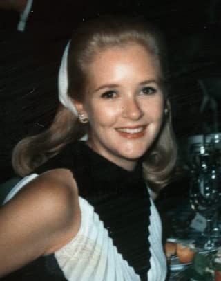 a woman sitting at a table smiling for the camera