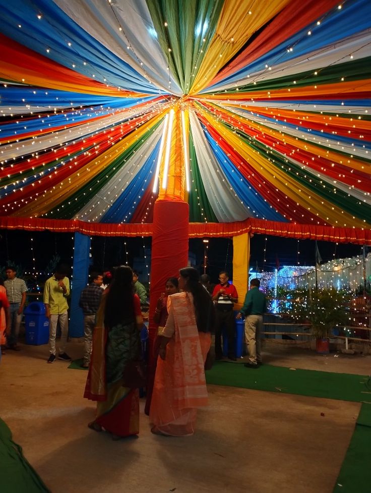 two women standing under a colorful tent with lights