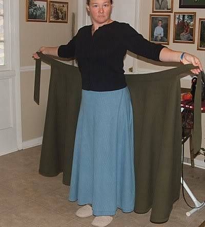 a woman standing in a living room holding onto a green skirt with her hands on the waist