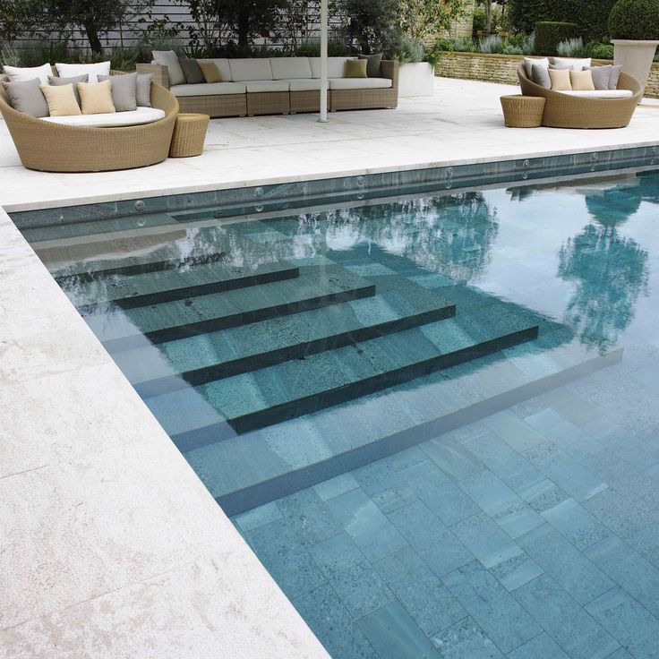 an outdoor swimming pool with lounge chairs and umbrella