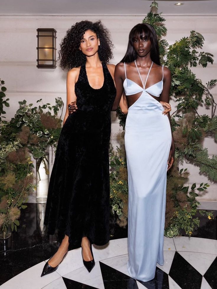 two women standing next to each other on a black and white checkerboard floor