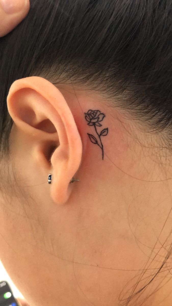 a woman's ear with a small rose tattoo on the back of her left ear