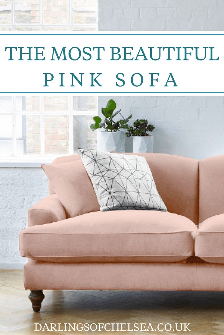 a pink couch in front of a white brick wall and potted plant on the floor