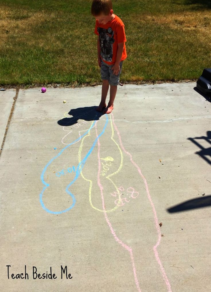 a young boy standing in front of a sidewalk with chalk drawings on it and the words teach beside him