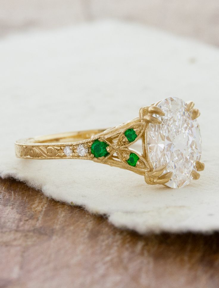 a close up of a ring with a diamond and green stones on it's side