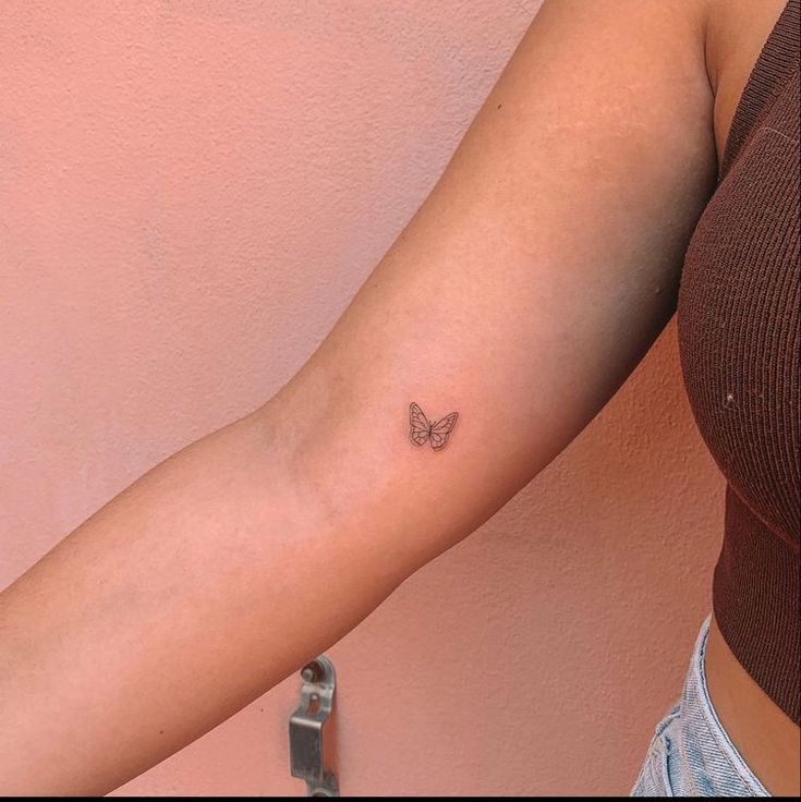 a woman's arm with a small butterfly tattoo on the left side of her arm