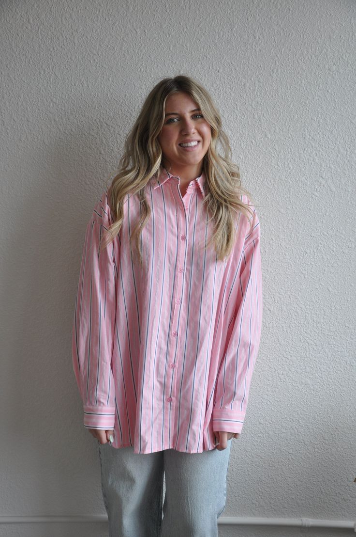 Introducing our Loose Fit Pink Striped Button Down, a stylish and versatile addition to your wardrobe. This button-down shirt features a relaxed, loose fit for ultimate comfort and ease of movement.Crafted from lightweight and breathable fabric, this shirt is perfect for both casual and dressy occasions. The pink stripes add a touch of femininity and sophistication, while the button-down design adds a classic and timeless appeal.The loose fit silhouette makes it easy to style and layer over your favorite tank tops or camisoles. Pair it with jeans or trousers for a chic and effortless look, or tuck it into a skirt for a more polished ensemble.Whether you're heading to the office, meeting friends for brunch, or enjoying a day out, our Loose Fit Pink Striped Button Down is sure to keep you lo Everyday Pink Button-up Shirt, Spring Daywear Shirt With Shirttail Hem, Spring Shirttail Hem Shirt For Daywear, Spring Daywear Shirt With Button Closure, Spring Everyday Shirt With Button Cuffs, Relaxed Button-up Spring Shirt, Relaxed Button-up Shirt For Spring, Spring Daywear Shirt With Relaxed Fit, Spring Shirt With Button Cuffs For Everyday Wear