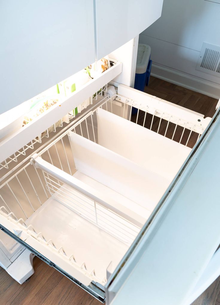 an open refrigerator with the door wide open and no ice maker in place on the floor