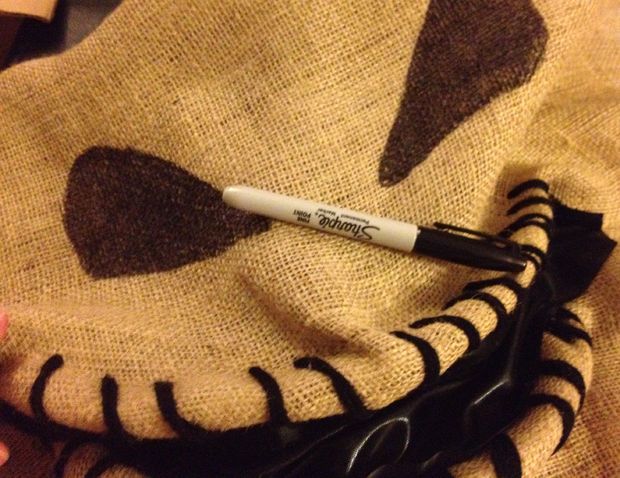 a person holding a pen on top of a piece of fabric with black and white designs