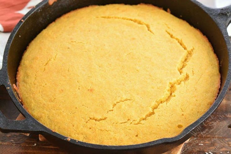 a cake in a cast iron skillet on a wooden table with an orange napkin