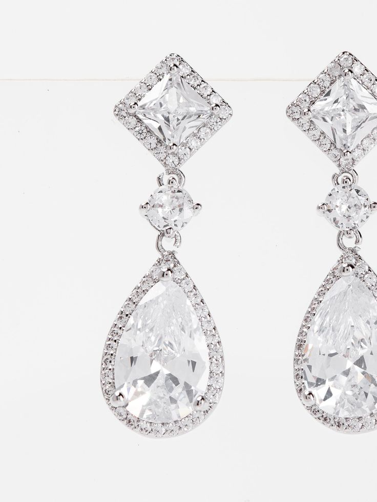 Expertly crafted with white gold plating, these Rhea earrings feature sparkling cubic zirconia drops that will add elegance to any outfit. The perfect balance of style and affordability, these earrings make a dazzling addition to your jewelry collection. SizeL: 1.2" QualityMade with quality materials for endurance. ImportedECZ1552 Dazzling Bridal Drop Earrings With Sparkling Stones, Diamond White Crystal Drop Earrings With Cubic Zirconia, Glamorous Diamond White Cubic Zirconia Earrings, Diamond Crystal Drop Earrings With Sparkling Stones, Diamond Drop Earrings With Sparkling Stones, Diamond White Diamond Crystal Drop Earrings, Sparkling Diamond Drop Bridal Earrings, Glamorous Cubic Zirconia Clip-on Earrings For Anniversary, Sparkling Diamond White Drop Chandelier Earrings