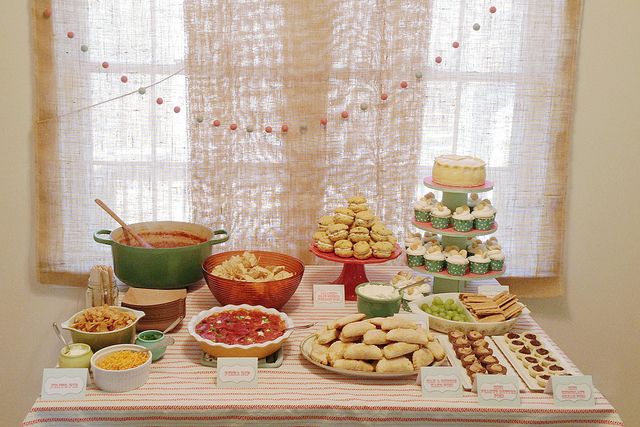 a table filled with lots of food next to a window covered in burlies