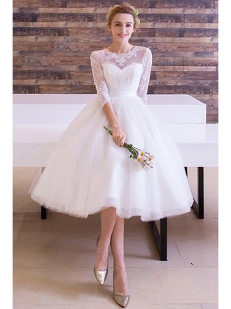 a woman is sitting on a bench wearing a white dress with sheer neckline and sleeves