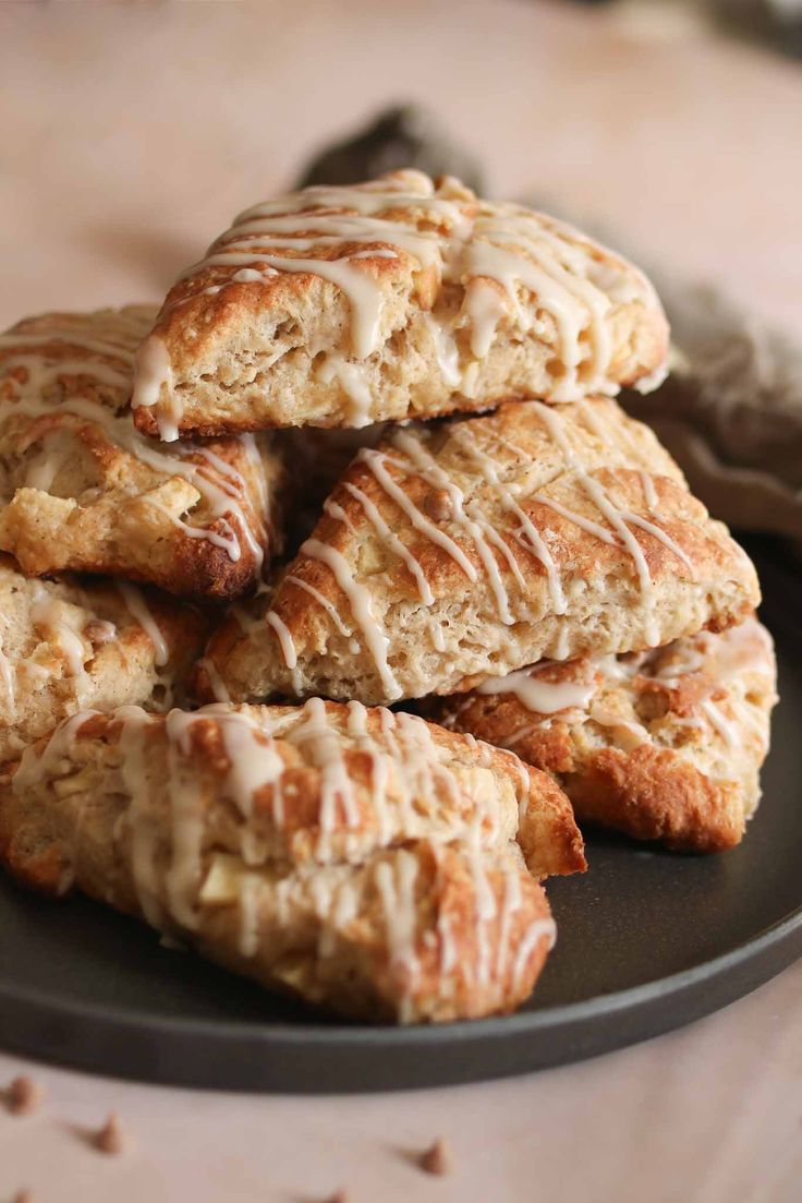 a pile of scones sitting on top of a black plate covered in icing