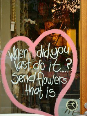 a pink heart painted on the side of a store front window that says, when did you want to do it? send flowers that is