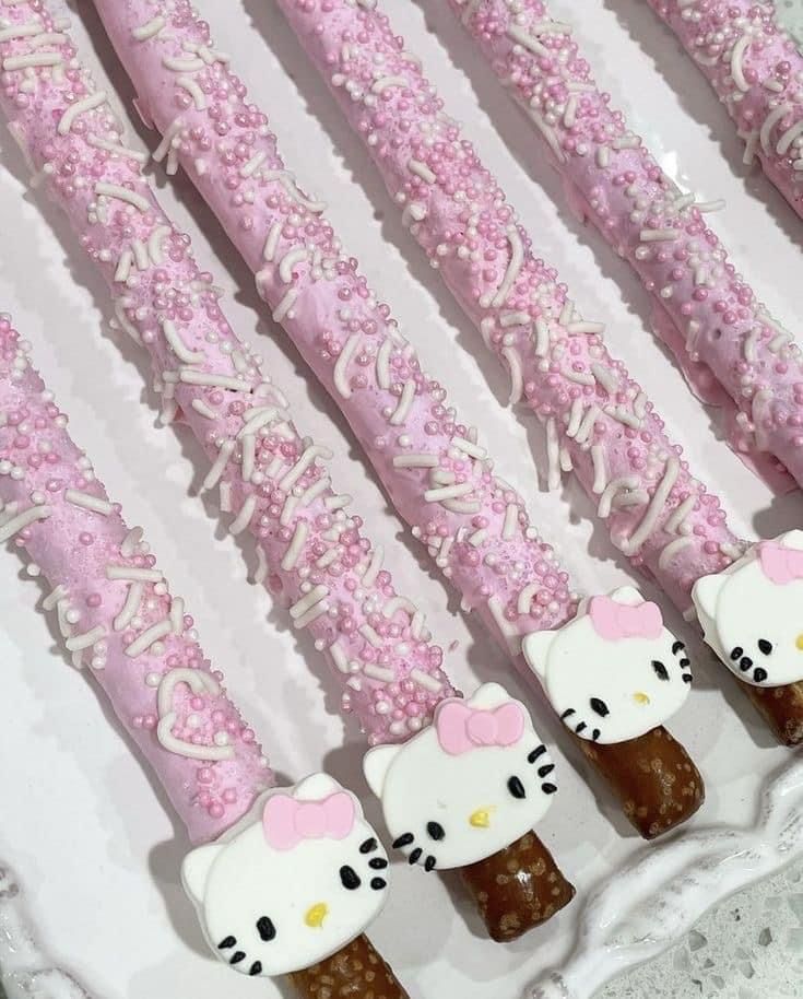 hello kitty cake pops are arranged in a row on a white plate with pink sprinkles