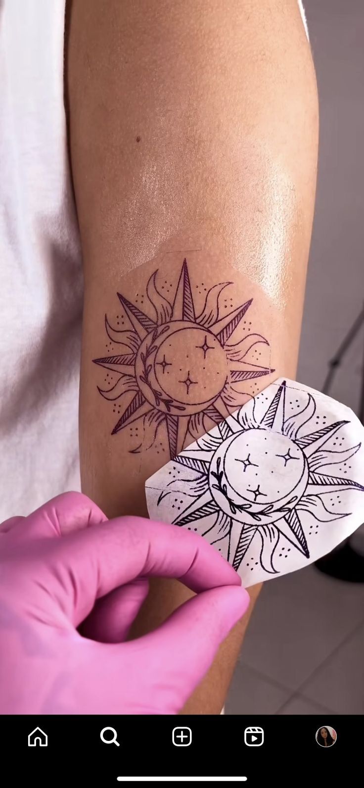 a person holding up a piece of paper with a sun and moon tattoo on it