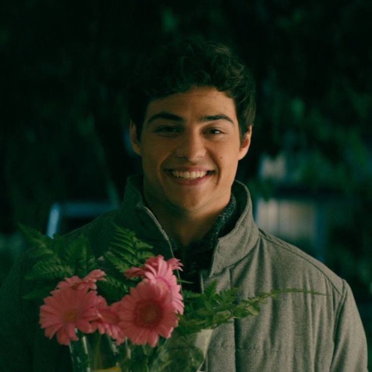 a young man holding a vase with flowers in it and smiling at the camera,