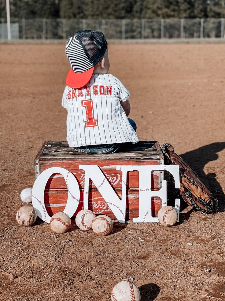 a little boy sitting on top of a wooden box with the word one written in it