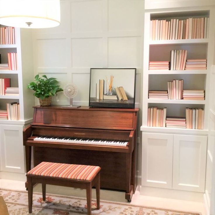 a piano in the corner of a room with bookshelves and a bench next to it