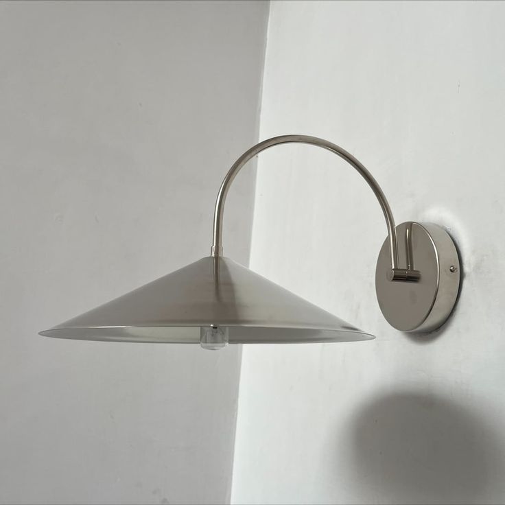 a wall light mounted on the side of a white wall next to a lamp shade