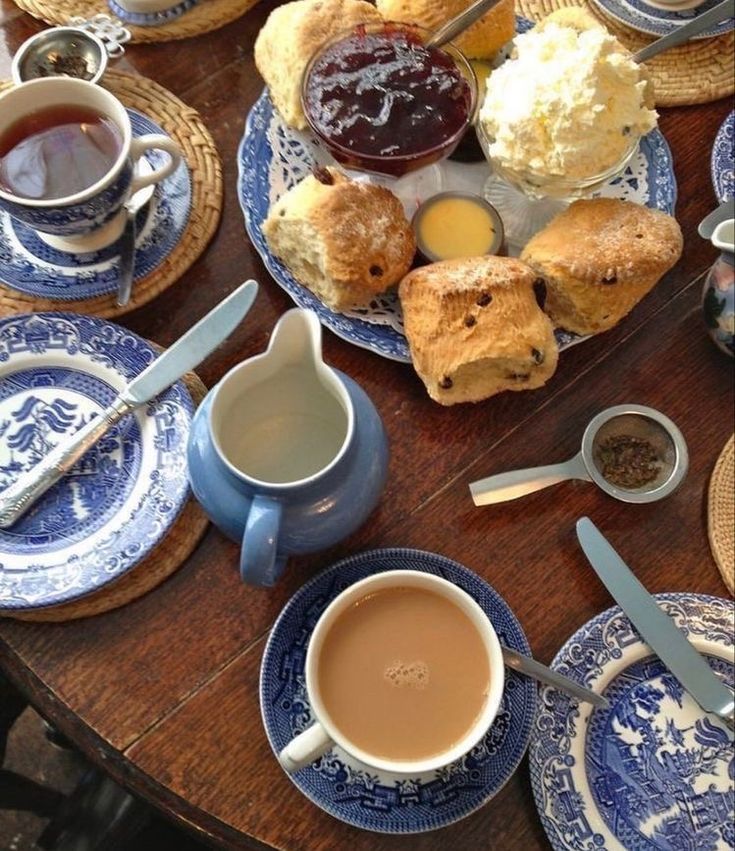 a table topped with blue and white plates filled with breakfast foods next to cups of coffee