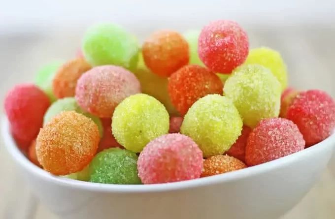 a white bowl filled with gummy bears on top of a wooden table