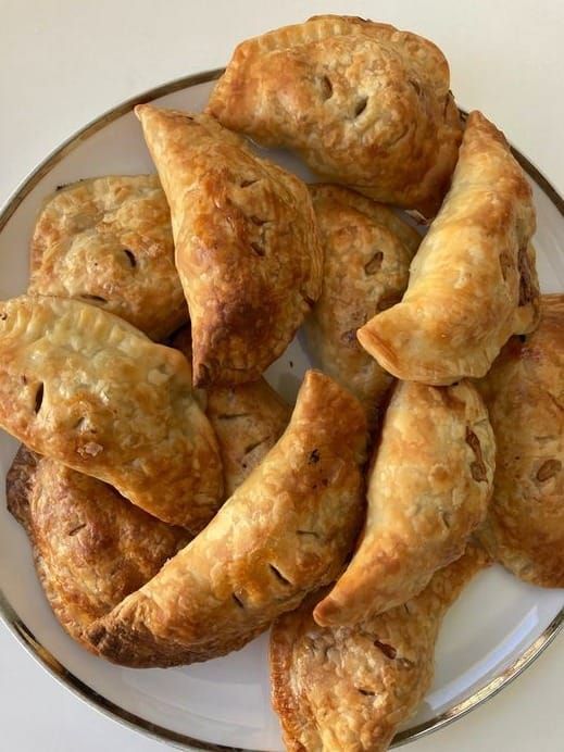 several pastries are arranged on a white and silver plate with a glass bowl next to it