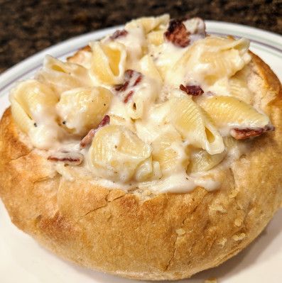 a white plate topped with a pastry filled with macaroni and cheese