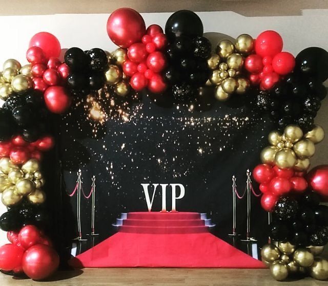 a red carpet with black and gold balloons