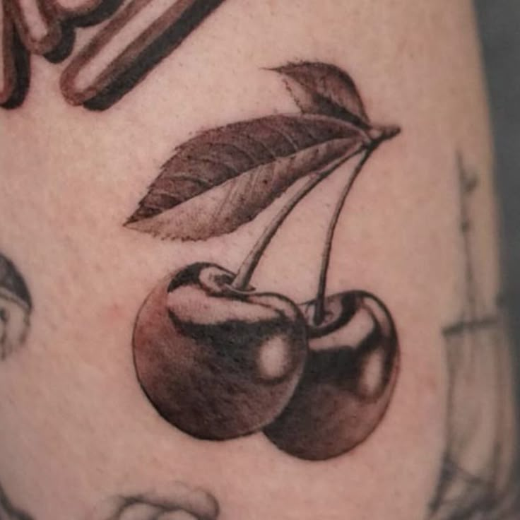 a close up of a tattoo with cherries on it