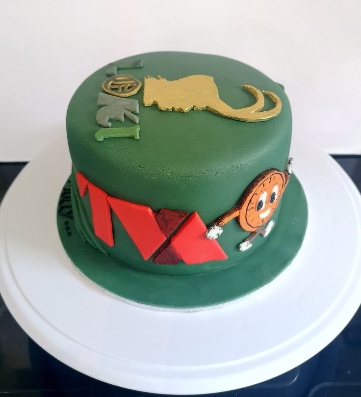 there is a green cake decorated with animals and letters on the top, sitting on a white plate