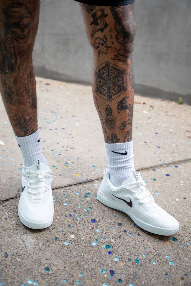 a man with tattoos on his legs wearing white sneakers