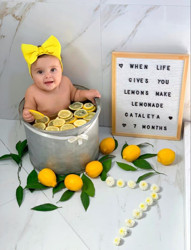 a baby sitting in a bucket with lemons