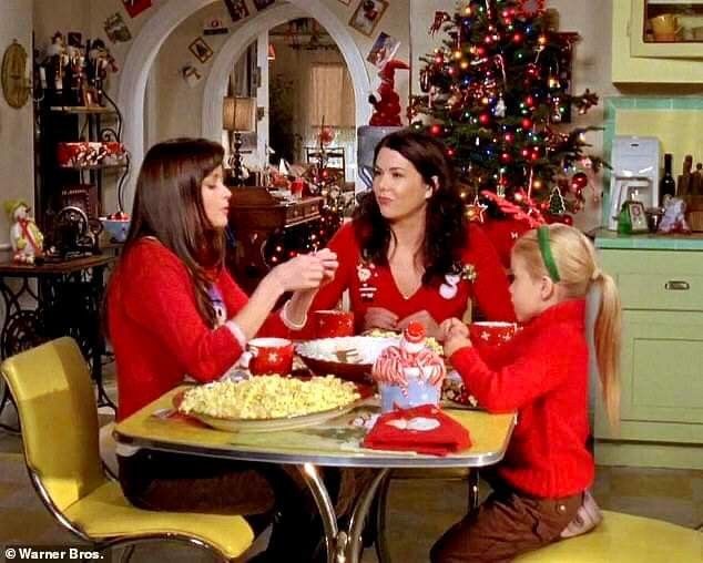 two women and a child sitting at a table with food in front of a christmas tree