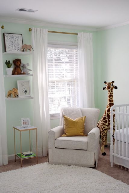 a baby's room with a giraffe stuffed animal on the wall and shelves